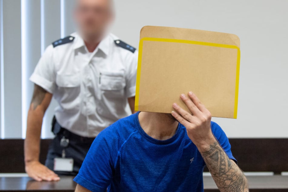 Ali Bashar (Re.) verdeckt sein Gesicht vor Gericht mit einem Papier-Umschlag