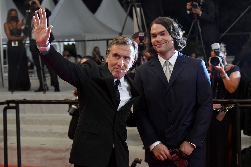 Tim Roth (l.) waves as he arrives with his son Cormac Roth for the screening of the film Bergman Island at the 74th edition of the Cannes Film Festival on July 11, 2021.