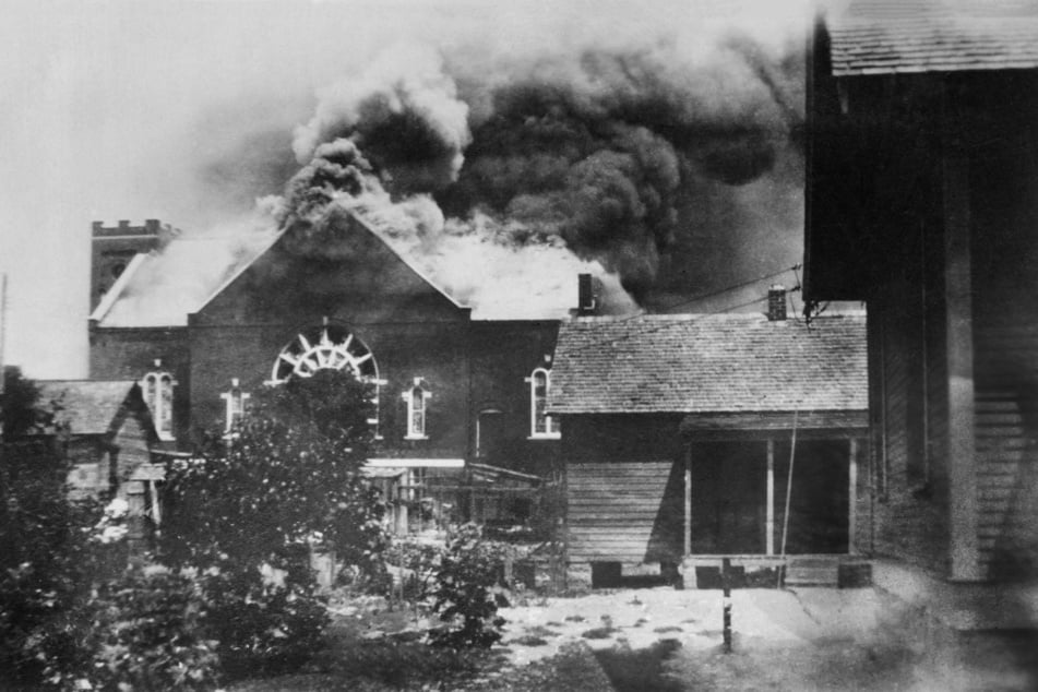 Enormous plumes of smoke rise from a burned church in the Greenwood District during the 1921 Tulsa Race Massacre.