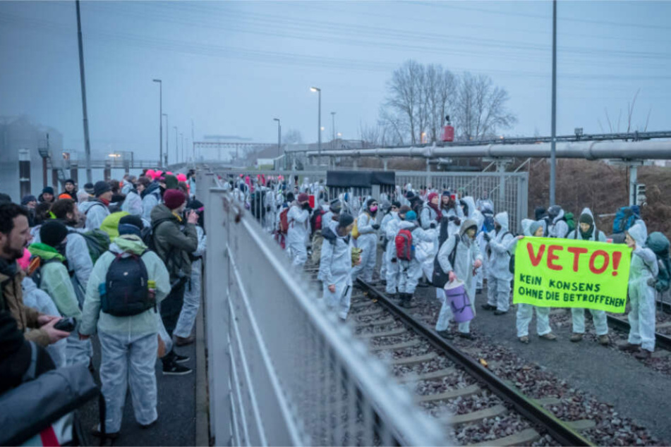 Demonstranten klettern übe rein Tor, dass aufs Kraftwerkgelände führt.
