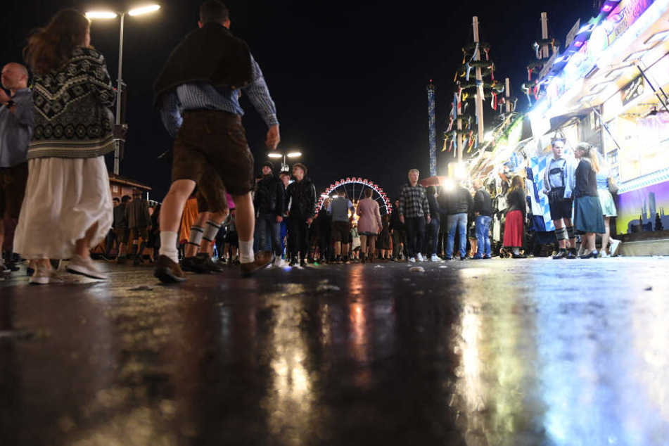 Die Lichter der Wiesn spiegeln sich auf dem nassen Straße auf der Theresienwiese. Am zweiten Wochenende kann es in München regnen.