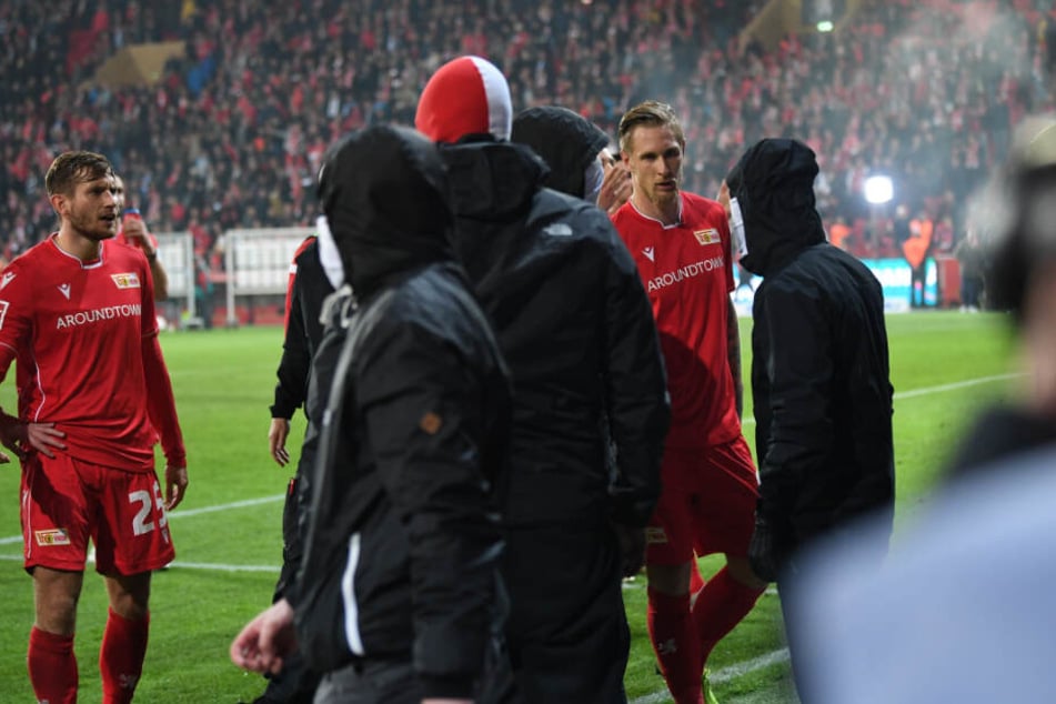 Unions Sebastian Polter (r) versucht nach dem Abpfiff und dem Sieg seines Teams im Derby vermummte Fans zu beschwichtigen.