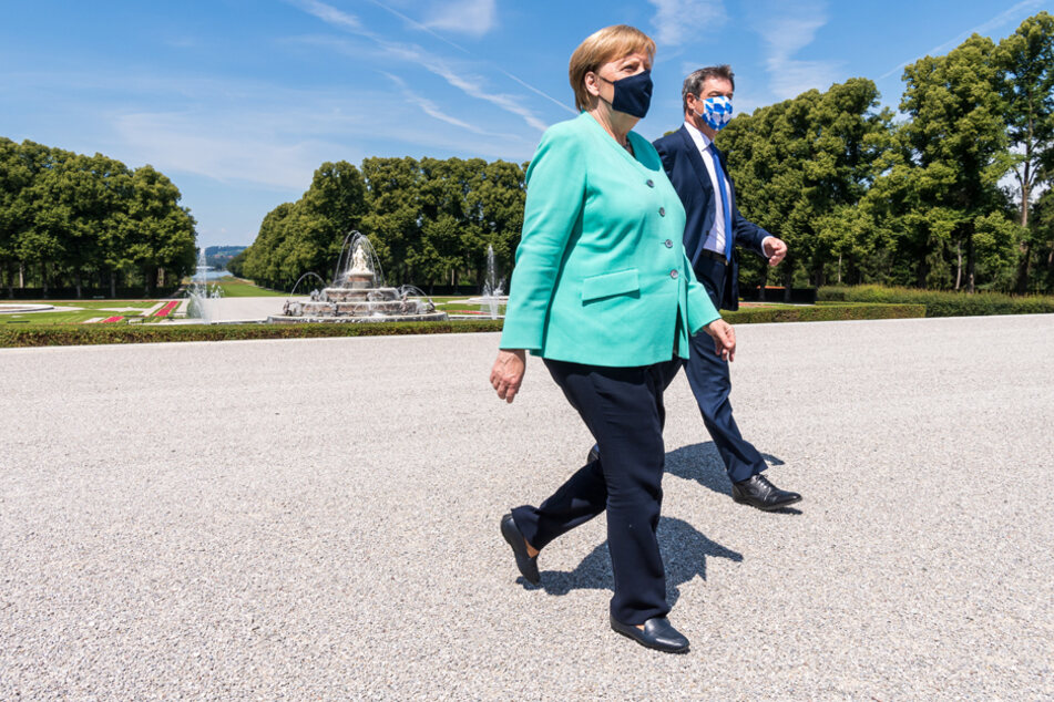 Markus Söder (CSU) und Bundeskanzlerin Angela Merkel (CDU) gehen nach einer gemeinsam Kutschfahrt zur Kabinettssitzung.