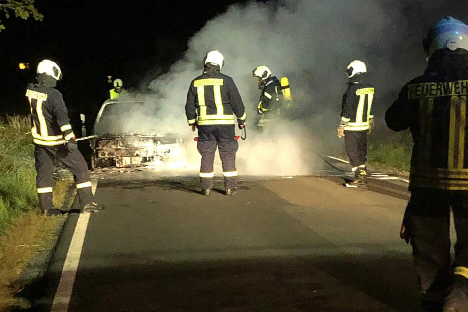 Die Einsatzkräfte löschen das Fahrzeug, welches augenscheinlich einen Totalschaden erlitten hat.