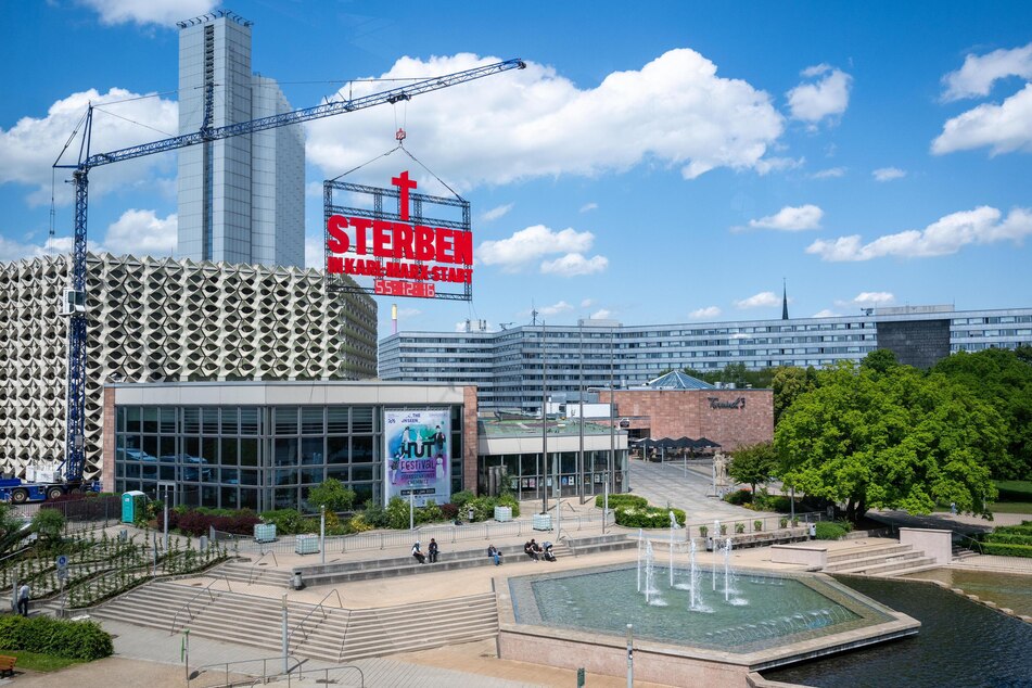 Seit Montag hängt an einem Kran ein riesiges Schild nahe der Stadthalle in Chemnitz.