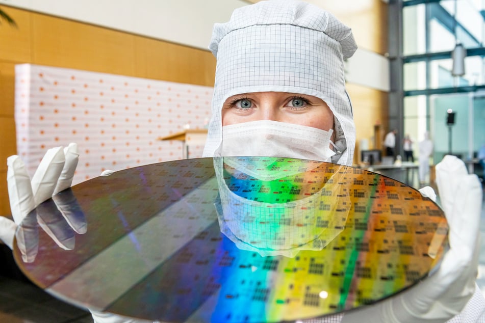 Eine Auszubildende von GlobalFoundries präsentiert einen 300-Millimeter-Wafer in der Dresdner Chipfabrik.