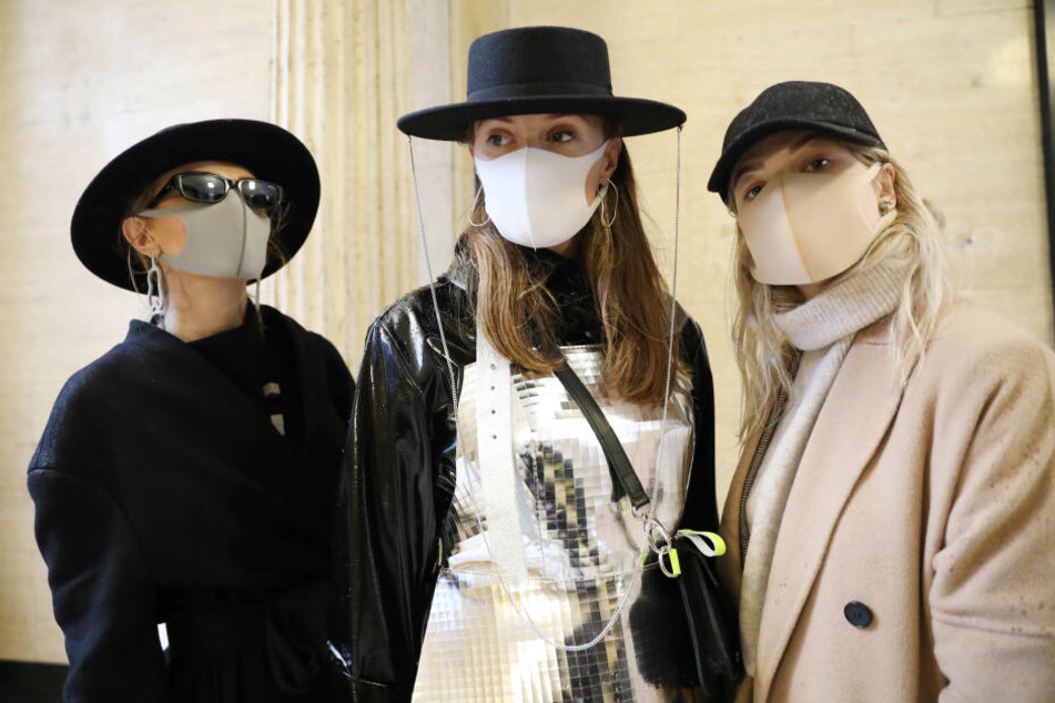 Besucher der Fashion Week aus Litauen tragen Gesichtsmasken und Kleidung der Modemarke kARTu während der London Fashion Week.