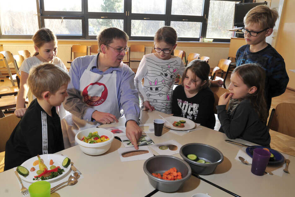 Wulf Karl (44) vom Gesundheitsamt schnippelt mit Grundschülern der Charles-Darwin-Grundschule bunte Zutaten für eine "gesunde Brotbüchse".