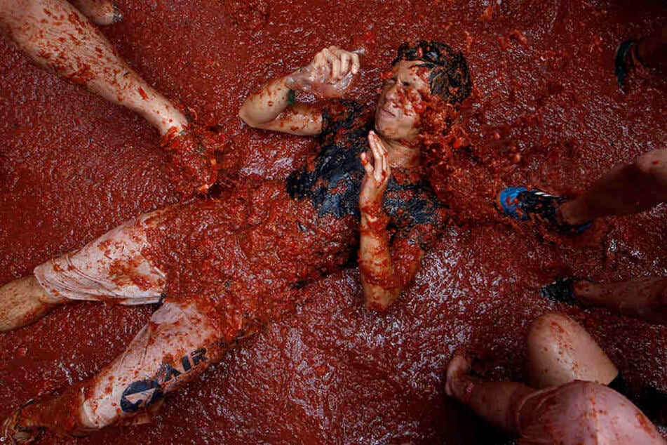 Ein Festteilnehmer liegt bei der traditionsreichen Tomatenschlacht "La Tomatina" inmitten zermatschter Tomaten.
