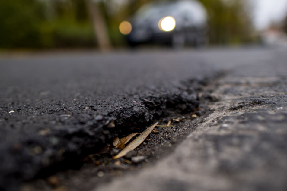 Autos fahren über den stark beschädigten Asphalt.