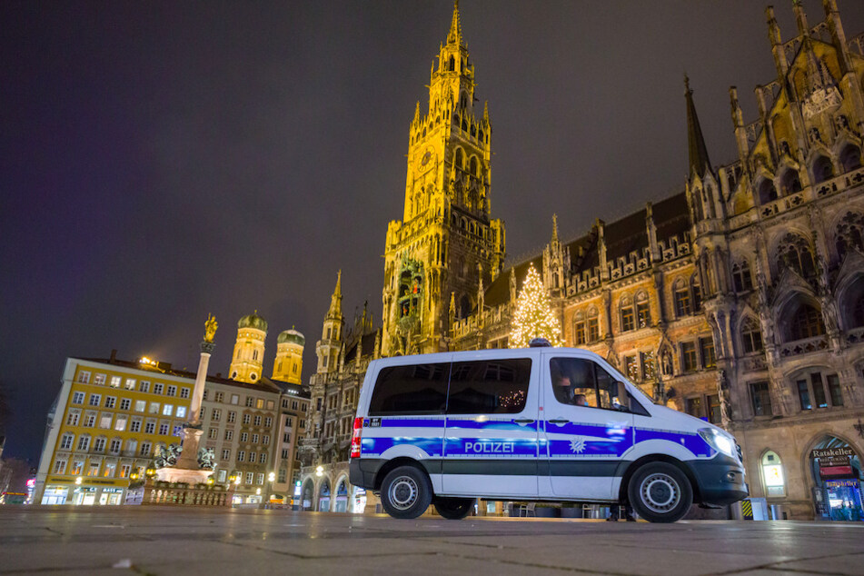 Ein Polizeiwagen fährt über den menschenleeren Marienplatz in München.