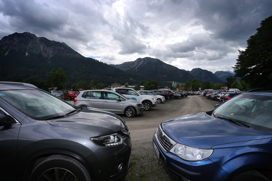 Autos von Ausflüglern stehen am Ortseingang von Oberstdorf auf einem Parkplatz.