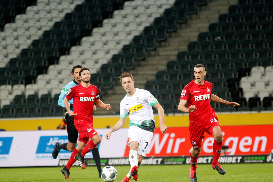 Der Mönchengladbacher Patrick Herrmann (M) und die Kölner Jonas Hector (l) und Ellyes Skhiri kämpfen um den Ball.