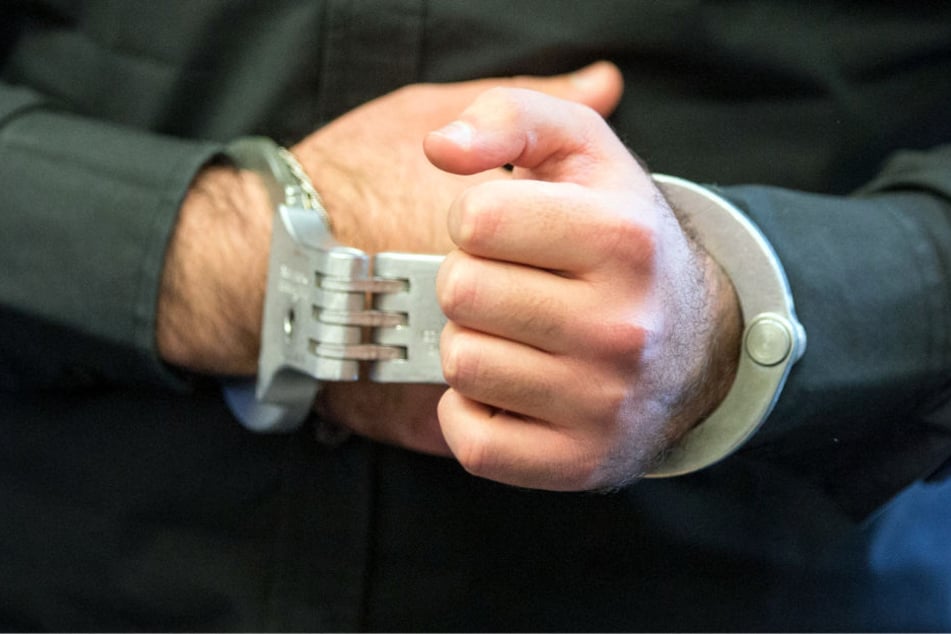 Einer der Angeklagten sitzt beim Prozessauftakt nach dem Tod eines Streitschlichters mit Handschellen im Sitzungssaal.