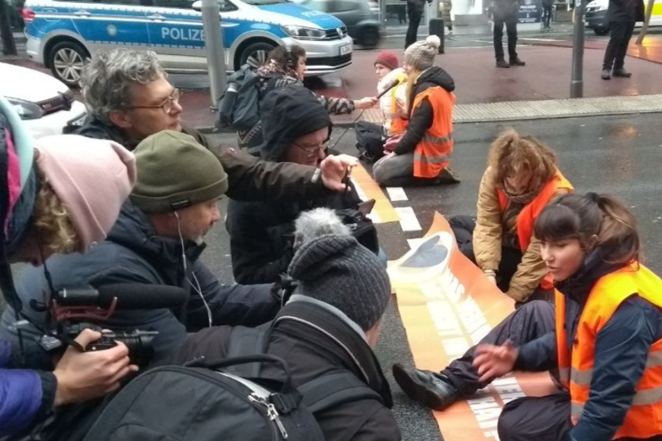 Klimaaktivisten sitzen auf der Straße am Potsdamer Platz in Berlin und blockieren den Verkehr.