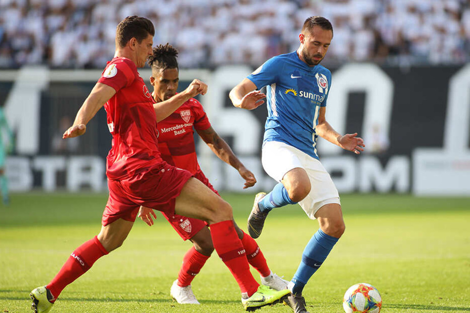 Ob es Rostocks Pascal Breier (r.) gefallen hat wie sein Mitspieler über ihn geredet hat? Stuttgarts Mario Gomez (l.) und Daniel Didavi dürfte es egal sein.