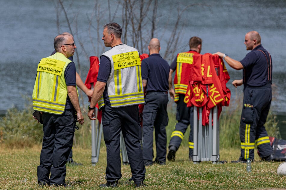 Feuerwehrleute stehen am kleinen Silbersee in Leverkusen. Aus dem See ist ein Mann tot geborgen worden.