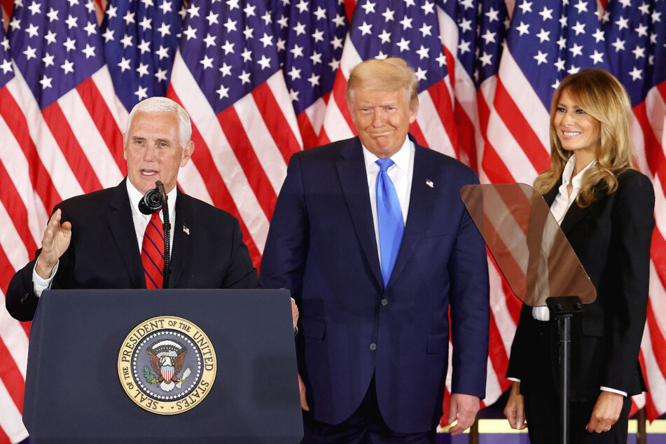 Mike Pence (l.) speaks as then President Donald Trump (c.) and first lady Melania Trump watch on election night in the East Room of the White House on November 4, 2020.