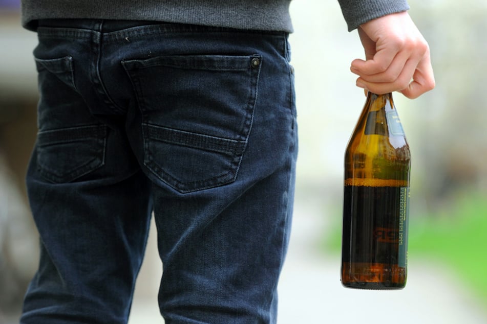 Ein Jugendlicher hält eine geöffnete Bierflasche in der Hand.