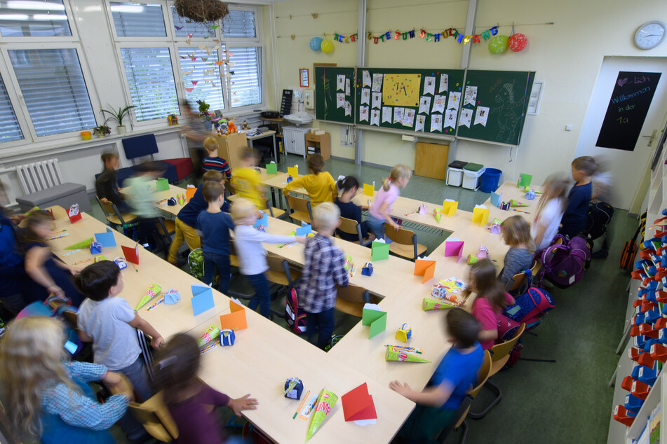 Grundschüler einer ersten Klasse setzen sich auf die Plätze in ihrem Klassenzimmer.
