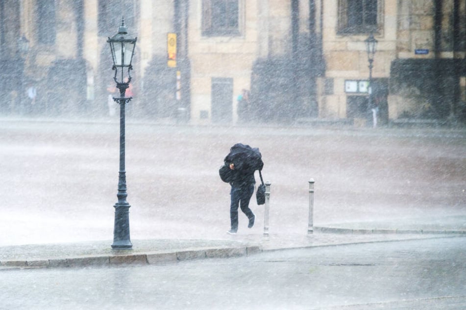 Ein Passant kämpft auf dem Theaterplatz gegen Sturm und Regen an.
