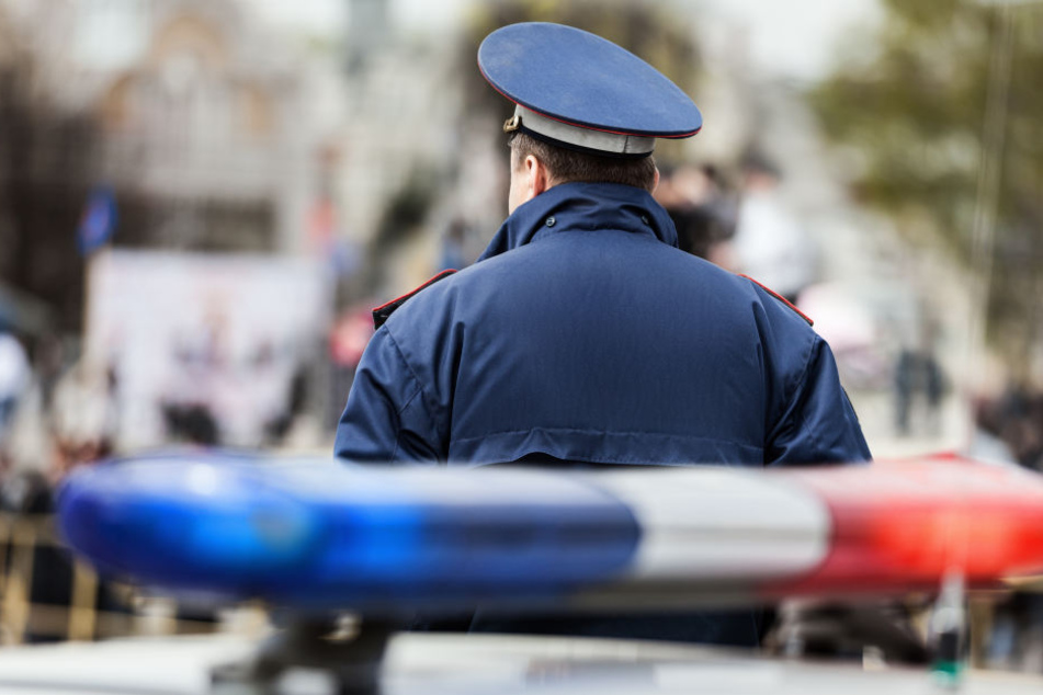 Beamter vor Polizeiauto (Symbolbild)