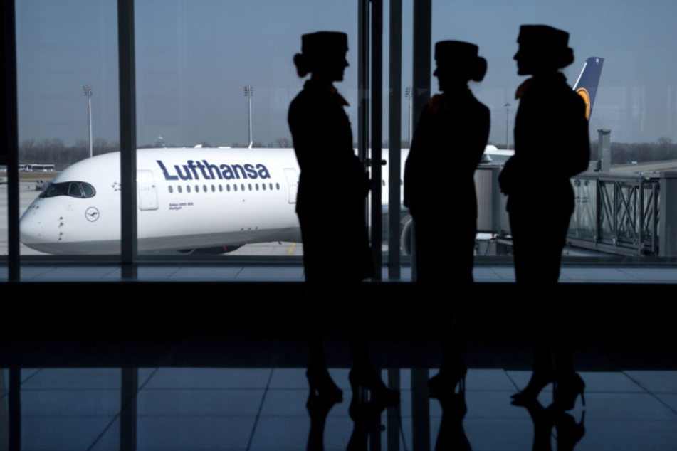 Stewardessen stehen vor einer Lufthansa-Maschine.