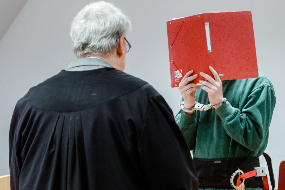 Januar 2018: Der Angeklagte verbirgt sein Gesicht hinter einem Aktenordner.