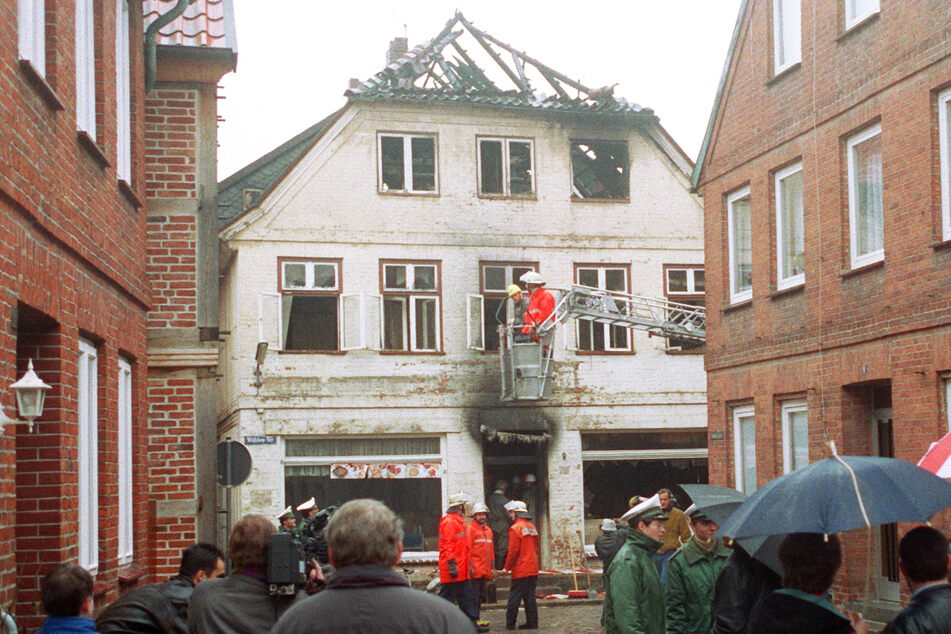 23. November 1992: Einsatzkräfte der Feuerwehr sichern das nach einem rechtsextremistischen Brandanschlag völlig ausgebrannte Haus in der Mühlenstraße in Mölln. (Archivfoto)