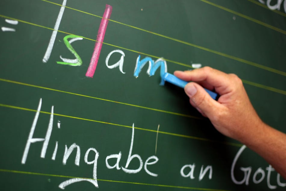 Ein Religionslehrer schreibt an einer Schule während des islamischen Religionsunterrichts an der Tafel. (Archivbild)