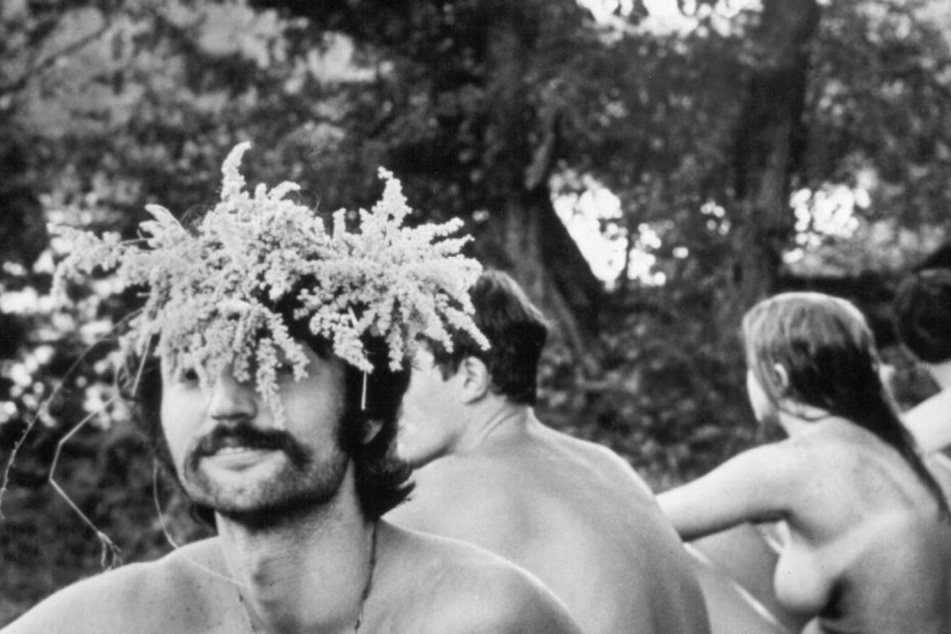 Einige unbekleidete Besucher sitzen im August 1969 beim Musikfestival Woodstock in Bethel.