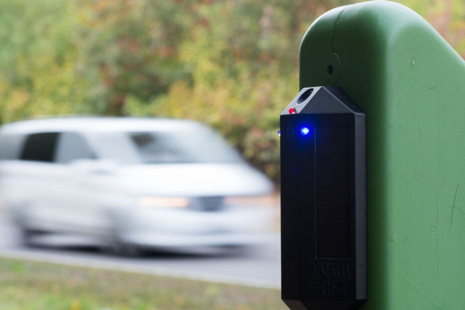 Ein an einem grünen Trägerpfosten montierter Wildwarner gibt als sich ein Fahrzeug nähert ein akustisches und optisches Signal ab. Die Signale wirken verstörend auf Wild und sollen die Tiere am Queren der Straße hindern.