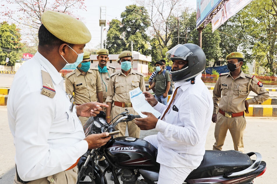 Ein Motorradfahrer zeigt bei einer Straßenkontrolle in Prayagraj Polizisten ein ärztliches Rezept.