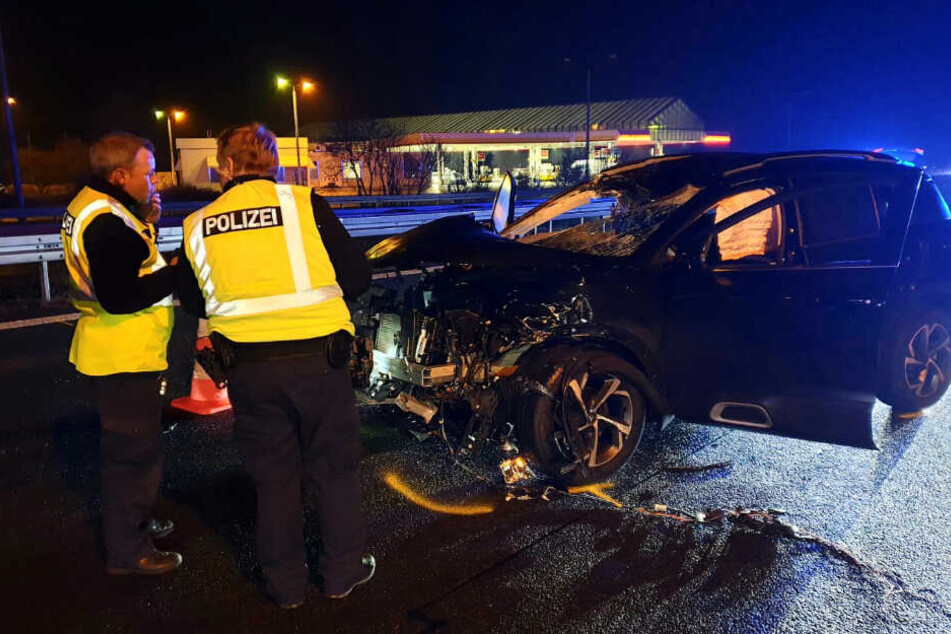 Polizisten stehen vor dem verunfallten Fahrzeug.