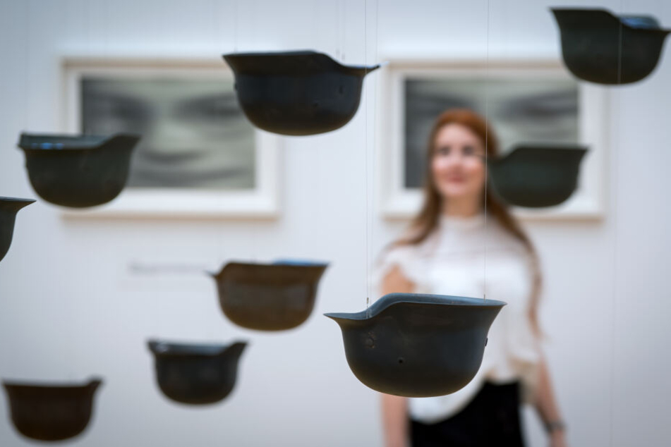 Die Arbeit "Helmets - Piece of Sky" zeigt Helme aus dem Zweiten Weltkrieg, die an Seilen von der Decke hängen. Viele der Werke, die Ono in Leipzig ausstellt, setzen sich mit den Themen "Krieg" und "Frieden" auseinander.