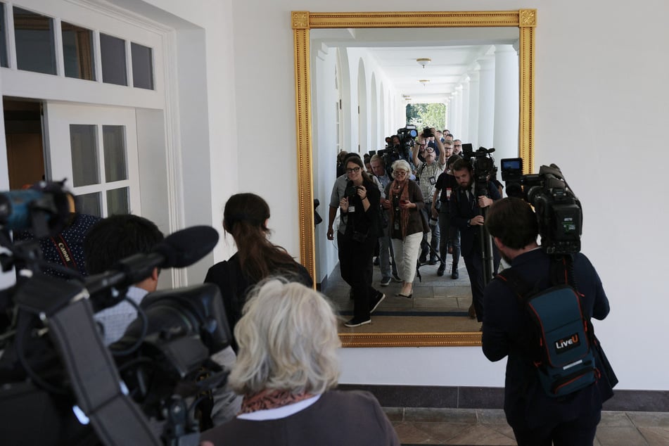 Journalists walk past a new mirror hanging on the wall of the White House Rose Garden Colonnade on August 22, 2025.