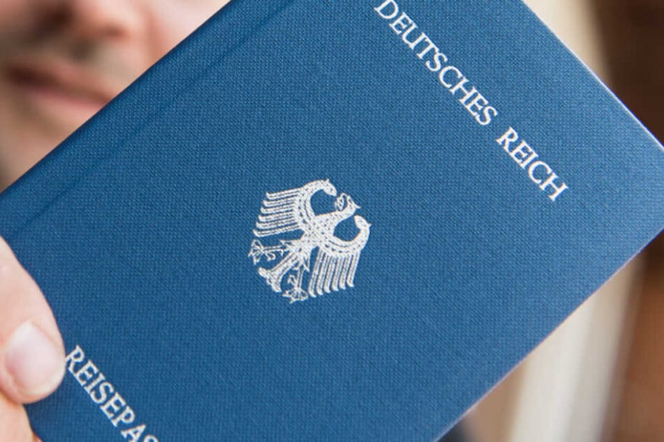 Ein Mann hält ein Heft mit dem Aufdruck "Deutsches Reich Reisepass" in der Hand. (Archivbild/Symbolbild)