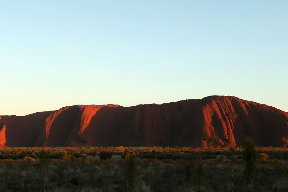 Die Sonne geht über dem Uluru auf. Betreten werden darf er jetzt von Touristen nicht mehr.