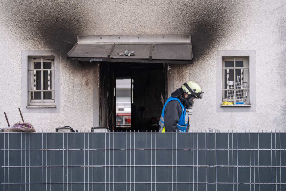 Ein Feuerwehrmann mit Atemschutzausrüstung verlässt nach einem Brand das Haus. Es wird längere Zeit nicht mehr bewohnbar sein.