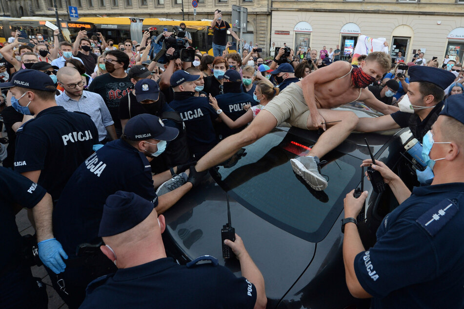 Ein Aktivist kletterte auf ein Polizeiauto, um gegen die Festnahme eines LGBT-Aktivisten zu protestieren. Der Vorfall ereignet sich am Freitag - inmitten steigender Spannungen in Polen zwischen LGBT-Aktivisten und einer konservativen Regierung, die gegen die Rechte von LGBT ist.
