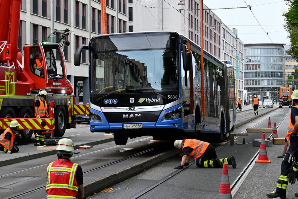 Der Kran hob den Bus an, sodass Feuerwehrleute Holzbohlen unter das Fahrzeug schieben konnten.