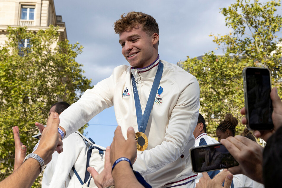 French swimmer Leon Marchand greets fans during the parade of French athletes who competed in the Paris 2024 Olympic and Paralympic Games.