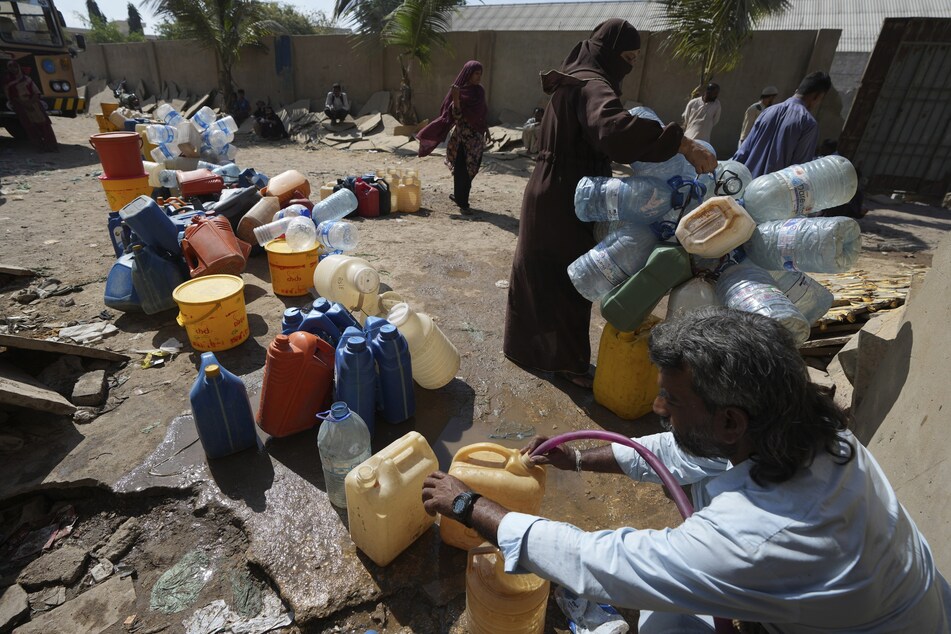 Menschen holen Trinkwasser aus einer Wasserentnahmestelle in einem Slumgebiet im pakistanischen Karachi.