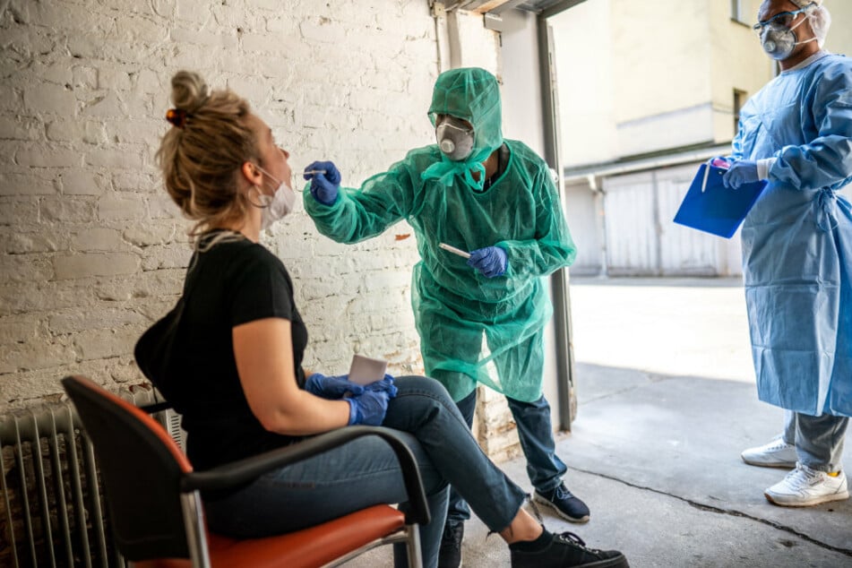 Beate Krupka (M), Fachärztin für Allgemeinmedizin und Praktikant Jose Persez nehmen an Clara, zum Test auf das Coronavirus, in einer Garage im Hinterhof der Arztpraxis in Kreuzberg einen Abstrich vor.