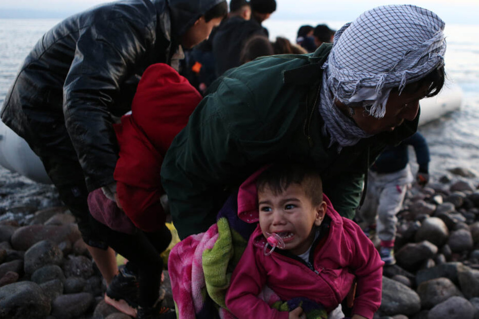 Flüchtlinge und Migranten verlassen nach ihrer Ankunft auf der griechischen Insel Lesbos ein Boot.