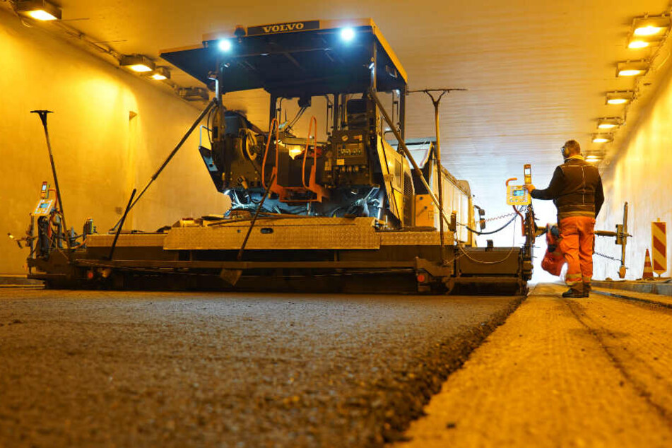 Arbeiter im Schwanenplatztunnel tragen neuen Fahrbahnbelag auf.