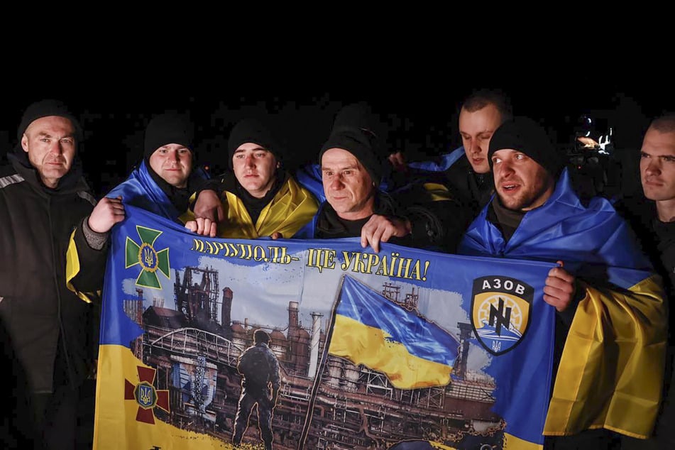 Ukrainische Kriegsgefangene halten nach einem Gefangenenaustausch eine Fahne mit der Aufschrift "Mariupol ist die Ukraine!" in den Händen.