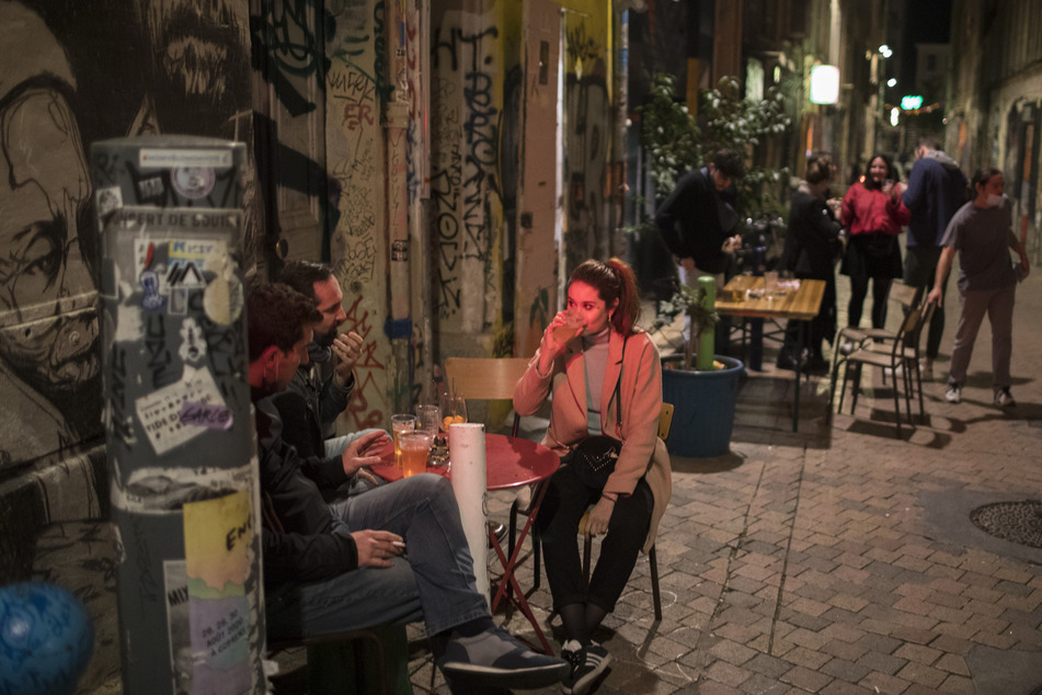Frankreich, Marseille: Freunde trinken ein Getränk vor einer Bar vor der Ausgangssperre.
