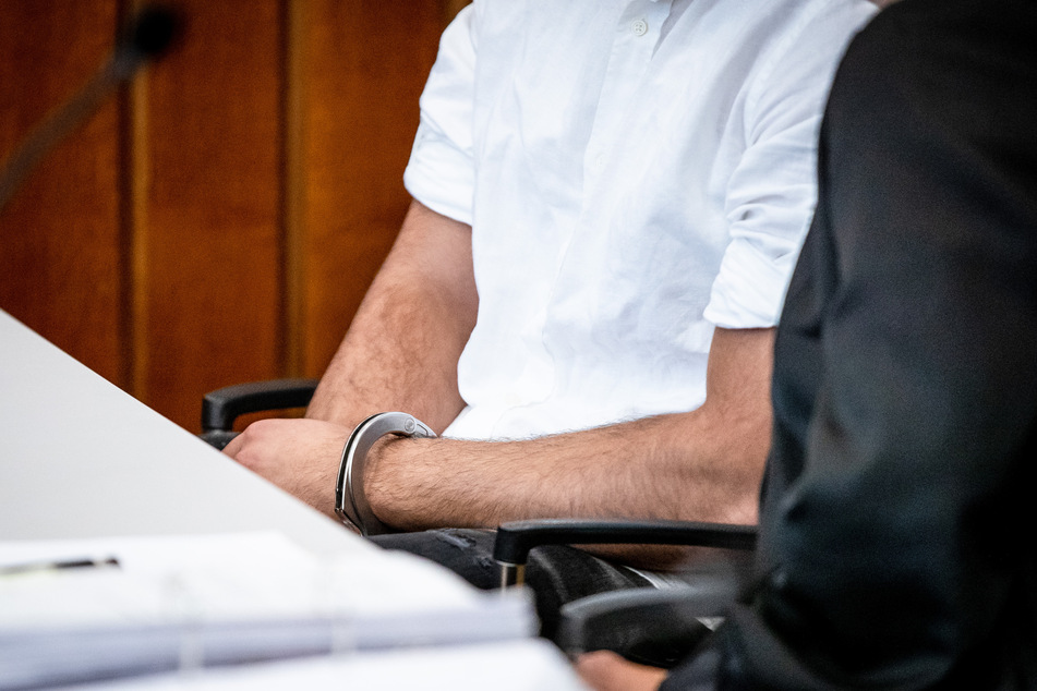 Der Angeklagte (21) sitzt mit Handschellen in einem Gerichtssaal des Landgerichts Heilbronn.