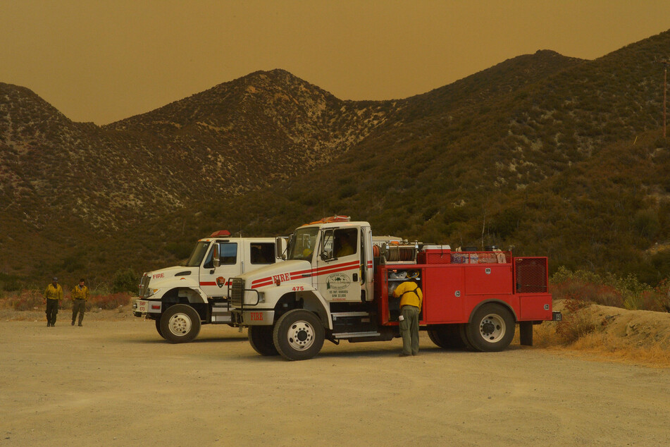 September, 21, 2020: firefighters rest on the Angeles Crest Highway as smoke from the Bobcat Fire envelops the San Gabriel Mountains in Juniper Hills, California.